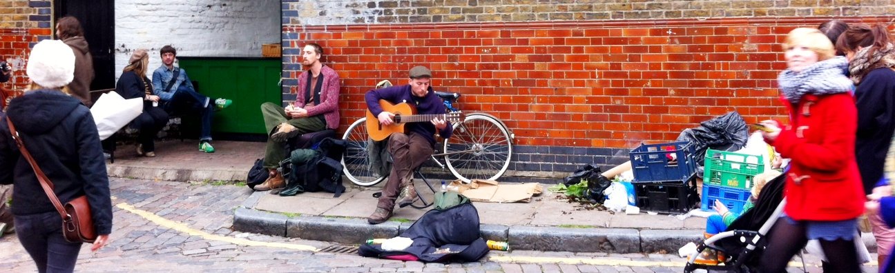 busker playing guitar at columbia road flower market london