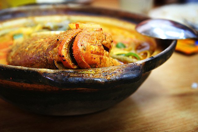 a bowl with a red snapper fish in it - fish head soup, Singapore
